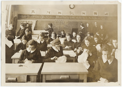 Reproduction d’une photographie d’une classe auxiliaire &agrave; l’&eacute;cole Routhier assistant &agrave; un cours de couture, Ottawa (Ontario), ca 1934.