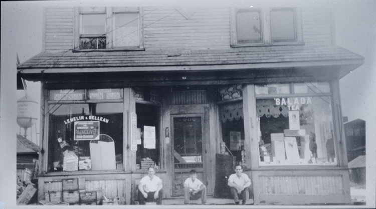 Reproduction d’une photographie du Magasin Lemelin et Belleau, au coin des rues Welland et Queen, Welland (Ontario), ca 1920.