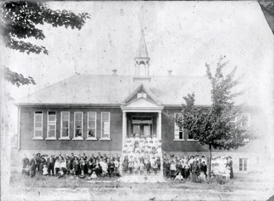 Reproduction d’une photographie des &eacute;l&egrave;ves devant l’&eacute;cole du village de Limoges (Ontario), 1914.
