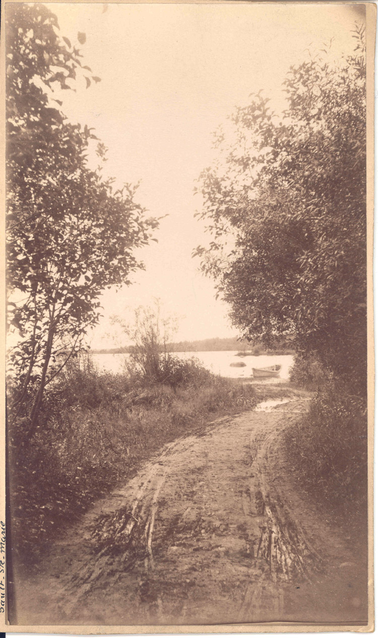 Reproduction d’une photographie d’un portage situ&eacute; sur la route des voyageurs de la Compagnie de la Baie d’Hudson &agrave; Sault-Sainte-Marie (Ontario), ca 1900.